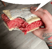 a person with a tattoo on their wrist is holding a toaster pastry with a bite taken out of it