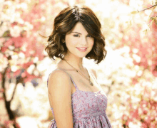 a woman in a purple dress stands in front of a tree with flowers