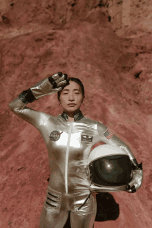 a woman in a nasa space suit holds her helmet