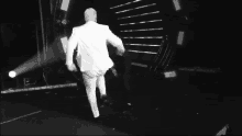 a man in a white suit is running on stage