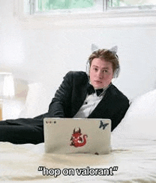 a man in a tuxedo is laying on a bed with a laptop and headphones .