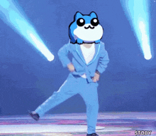 a man in a blue suit is dancing on a stage with a cat on his head .