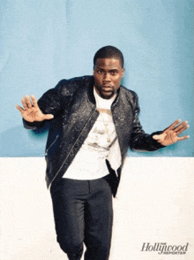 a man standing in front of a blue wall with hollywood reporter written on the bottom