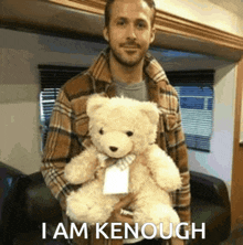 a man in a plaid shirt is holding a teddy bear with the words " i am kenough " below him