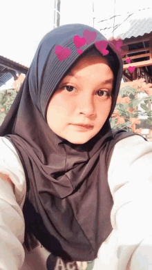 a girl wearing a hijab with hearts on it looks at the camera