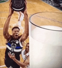 a basketball player is jumping over a glass of milk on a court .