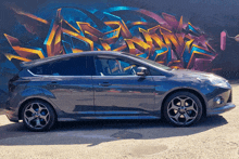 a car is parked in front of a graffiti wall