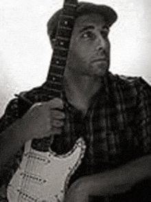 a man in a plaid shirt is holding a guitar in his hands .