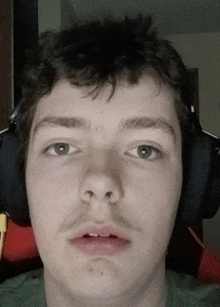 a young man wearing headphones looks at the camera with a serious look on his face