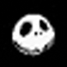 a black and white image of a skull with a smiley face on a black background .