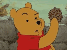 a cartoon of winnie the pooh holding a pine cone in his hand .