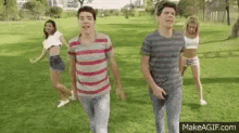 a group of young people are dancing in a park while walking through the grass .