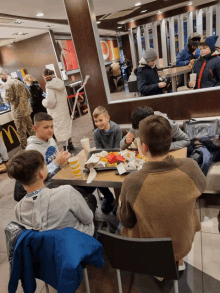 a boy wearing a nasa shirt sits at a table in a mcdonalds