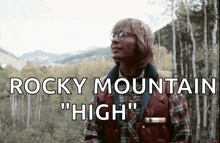 a man in a plaid shirt is standing in the woods with the words rocky mountain " high " behind him