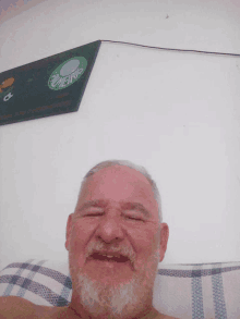 a man with a beard is smiling in front of a palmeiras sign