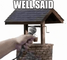 a person is holding a microphone in front of a well that says well said .