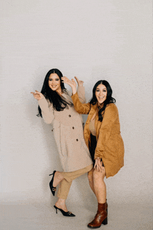 two women standing next to each other with one pointing at the camera