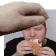 a man is eating a chicken nugget and a hand is reaching out to take a bite .