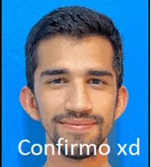 a man with a beard is smiling in front of a blue background with confirmo xd written below him