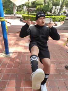 a boy wearing a champion beanie is sitting on a swing