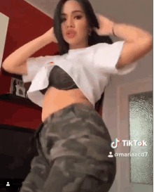 a woman wearing a bra and camo pants has a tiktok icon on her bottom