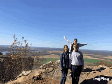 a man and woman standing on top of a rocky hill with a child on their shoulders and the words imgplay below them