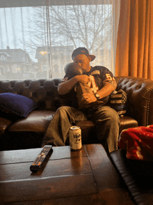 a man is sitting on a couch with a can of moonshine on the table