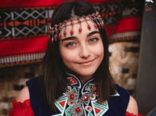 a woman wearing a headband and a necklace is smiling for the camera .