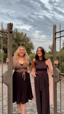 two women are standing next to each other behind a gate