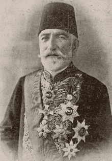 a man with a beard and mustache is wearing a hat and a coat with a lot of medals on it