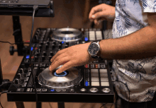 a man wearing a watch is playing music on a mixer