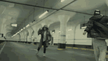 a man wearing a black hat with the word amen on it walks with a woman in a parking garage