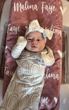 a baby is wrapped in a blanket with the name malina faye written on it