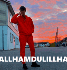 a man in a red hoodie is standing in front of a building with the words allhamdulillha written below him