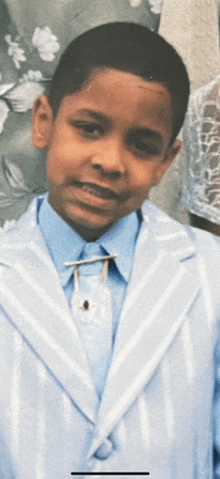 a young boy wearing a blue and white suit and tie