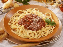 a plate of spaghetti with meat sauce and cheese on a table with a fork .