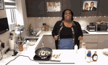 a woman is cooking in a kitchen with a picture of a man and woman on the wall above her