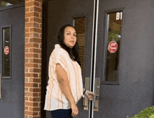 a woman is standing in front of a door that has the number b1 on it