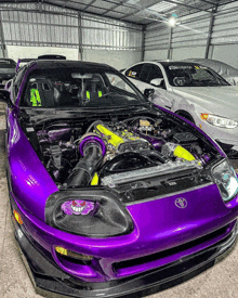 a purple toyota supra is parked in a garage with the hood open