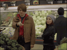 a man pointing at a woman in a grocery store with a sign that says ' acorn ' on it