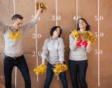 a man and two women holding pom poms in front of a scoreboard that says 30 40 50 and 60