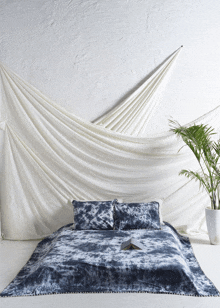 a bed with a blue and white tie dye blanket and pillows