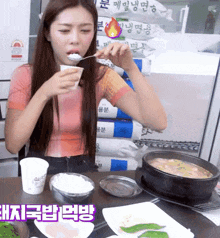 a woman is eating rice with a spoon in front of a pile of bags that say ' rice ' on them