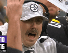 a man wearing a hat that says steelers holds his hands in the air