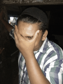 a man covering his face with his hands in a striped shirt