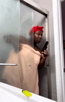 a woman wrapped in a towel holds a gun in a shower stall