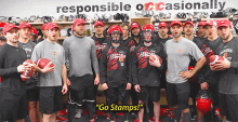 a group of football players standing in a locker room with the words " go stamps " written on the wall behind them