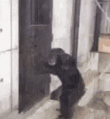 a person is kneeling down in front of a door in a bathroom .