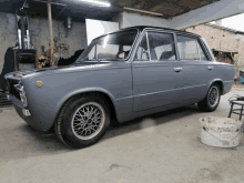 a gray car is parked in a garage next to a bucket that says ' asphalt ' on the side