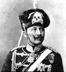 a black and white photo of a man in a military uniform with a skull hat on his head .